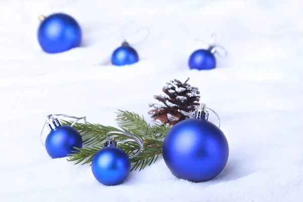 Merry Christmas background with blue balls, christmas tree on snow with snowflakes falling from a blue sky. Stock Picture