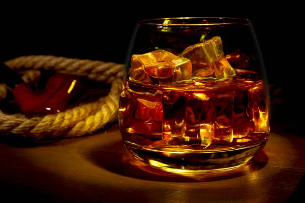 Glass of whiskey, cognac or brandy with ice and smoking pipe on wood table. Top view with copy space — Stock Photo, Image