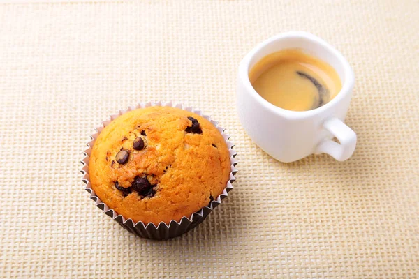 Perfect ontbijt met heerlijke zelfgemaakte cupcakes met rozijnen, chocolade chips en espressokoffie in witte cup op textiel achtergrond. Muffins. — Stockfoto