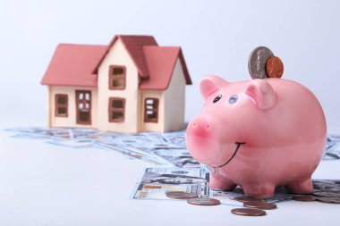 Gayrimenkul veya ev tasarrufu. Bulanık arka plan parası ve evi olan domuz kumbarası..