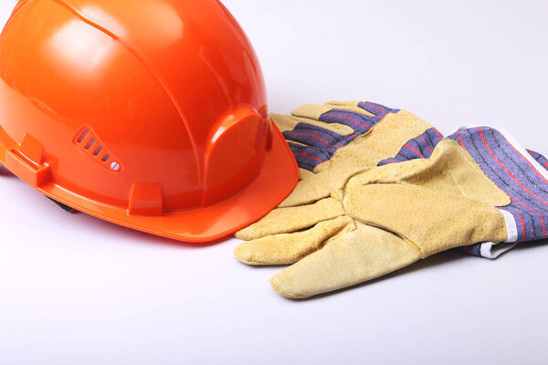 Оранжевая жесткая шляпа, когти и защитные перчатки на белом фоне
.