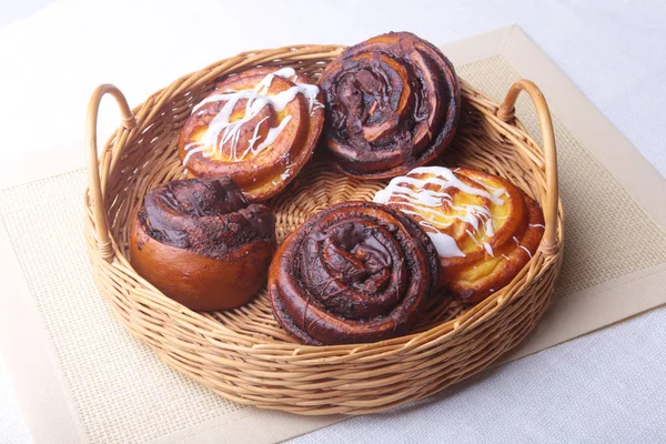 Freshly baked homemade sweet bun or sweet rolls with cinnamon in a wicker basket. — Stock Photo, Image