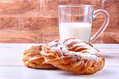 Çikolata ve pudra şekeri krem puf yüzük ve ahşap masa üzerinde süt ile cam. geleneksel kahvaltı.