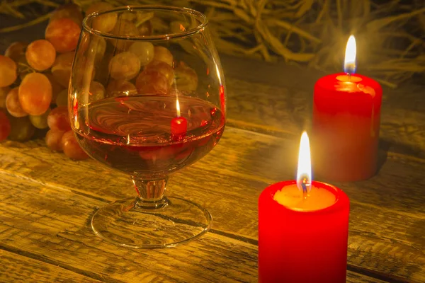 Glass with Cognac or Brandy, fresh grapes and candles. still life in rustic style, vintage wooden background, selective focus. — Stock Photo, Image