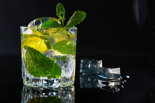 Szklanka koktajlu z rum, limonka, kostki lodu i mięty pozostawia na tle czarnego lustra. — Zdjęcie stockowe