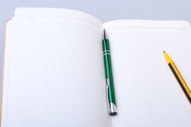 Açık boş sayfa defter ve kalem beyaz masada.