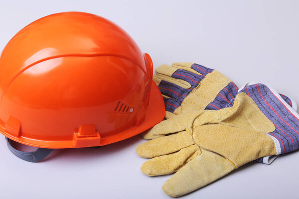 Оранжевая жесткая шляпа, когти и защитные перчатки на белом фоне
.