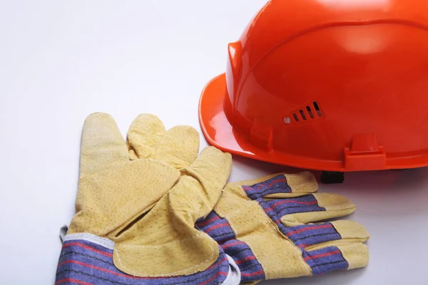 Orange hard hat, goggles and safety gloves on a white background.