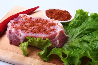 Otlar, biber ve baharat kesme tahtası üzerinde çiğ domuz biftek. Barbekü için hazır.