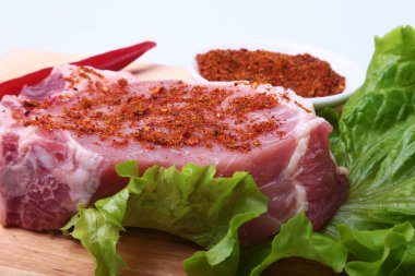 Otlar, biber ve baharat kesme tahtası üzerinde çiğ domuz biftek. Barbekü için hazır.