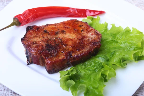 Bife de carne no churrasco e pimenta com tomate, folhas de alface no prato branco — Fotografia de Stock