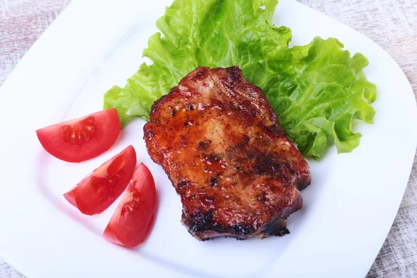 Steak sapi pada barbeque dan cabai dengan tomat, daun selada di piring putih — Stok Foto