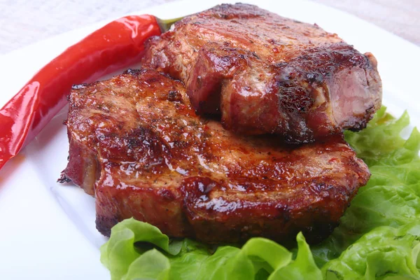 Bife de carne no churrasco e pimenta com tomate, folhas de alface no prato branco — Fotografia de Stock