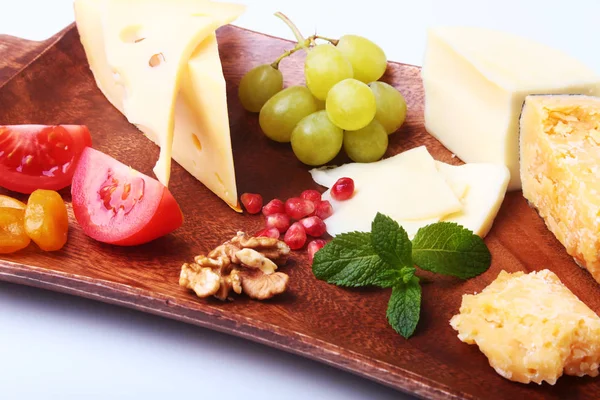 Assortiment van kaas met fruit, druiven, noten en kaas mes op een houten dienblad. — Stockfoto