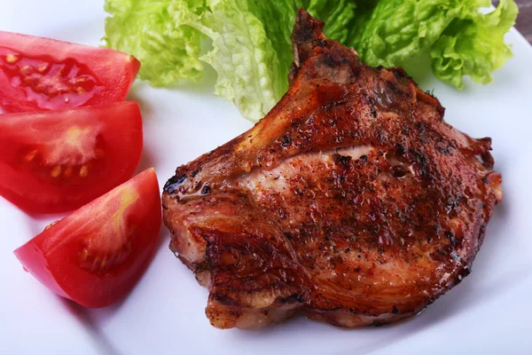 Daging babi panggang dengan tomat, daun selada dan saus tomat di atas piring . — Stok Foto