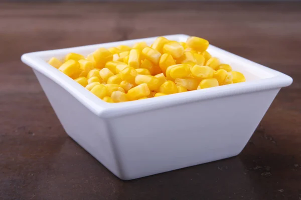 Sweet canned corn in white bowl. Ingredients for salad. Selective focus.