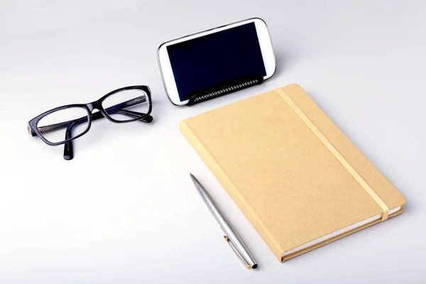 Modern white office desk table with laptop, smartphone and other supplies. Blank notebook page for input the text in the middle. Top view. Stock Image