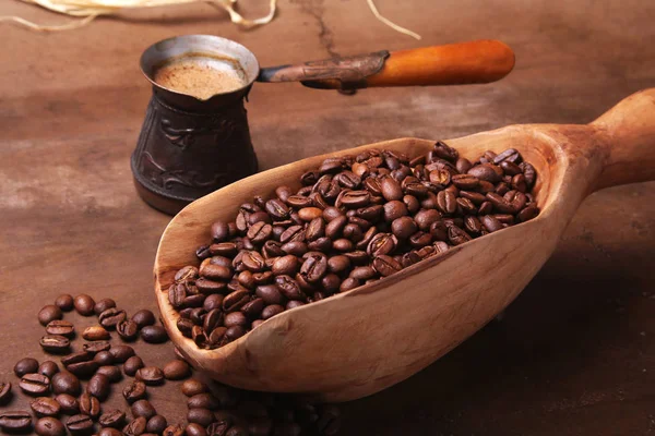 Vieja cucharada de madera con granos de café, molinillo de café y café turco en Cezve en mesa de piedra oscura . — Foto de Stock