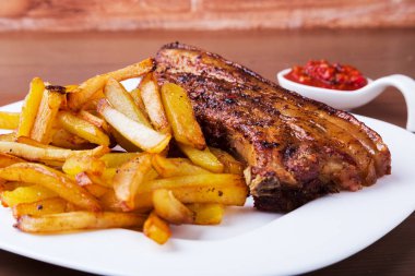 Beyaz plaka üzerinde patates ücretsiz ve sos ile ızgara domuz kaburga.