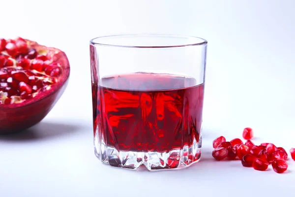 Glas med granatäpple juice granatäpplekärnor och vacker mogen granatäpple på vit bakgrund med plats för kopia utrymme. — Stockfoto