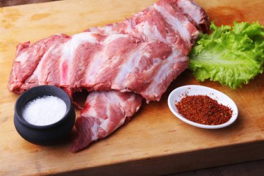 Tuz, biber ve baharat değirmeni ile bir rustik kesme tahtası üzerinde ham kaburga. kopya alanı. Üstten Görünüm.