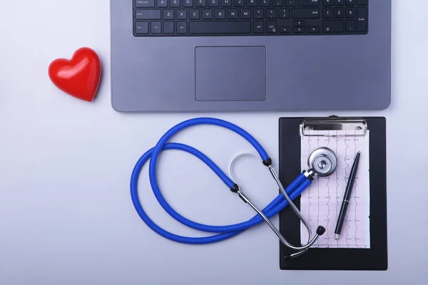 Lugar de trabajo del médico con portátil, estetoscopio, prescripción RX, gafas y corazón rojo y portátil en la mesa blanca. Vista superior. Copiar espacio . — Foto de Stock