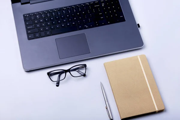 Primer plano del cómodo lugar de trabajo en la oficina con computadora portátil, portátil, gafas, bolígrafo y otros equipos colocados en la mesa con espacio para copias . —  Fotos de Stock