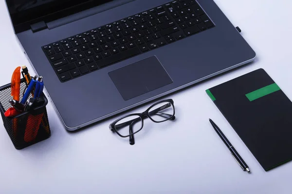 Primer plano del cómodo lugar de trabajo en la oficina con computadora portátil, ratón, portátil, gafas, bolígrafo y otros equipos que ponen en la mesa con espacio para copias. Vista superior . —  Fotos de Stock