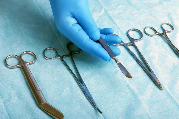 Detalle plano de instrumentos de cirugía esterilizada con una mano agarrando una herramienta  , — Foto de Stock