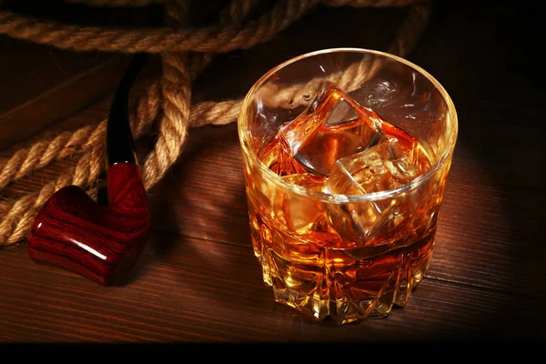 Ahşap arka planda viski, buz küpleri ve sigara borusu ile cam. — Stok fotoğraf