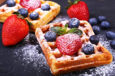 Siyah tabakta taze meyve, çilek ve toz şeker ile ev yapımı Geleneksel Belçika waffle.