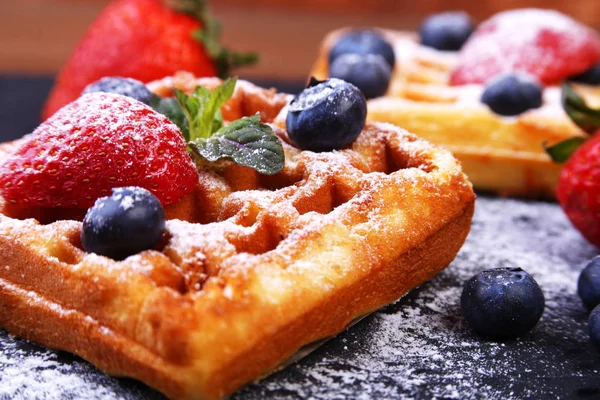 Waffles belgas tradicionais caseiros com frutas frescas, bagas e açúcar em pó na placa preta . — Fotografia de Stock