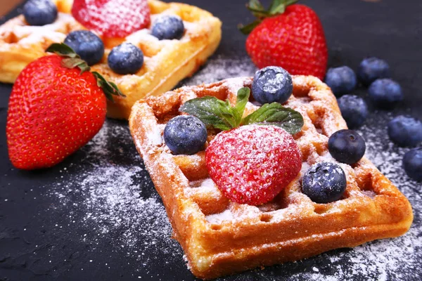 Waffles belgas tradicionais caseiros com frutas frescas, bagas e açúcar em pó na placa preta . — Fotografia de Stock