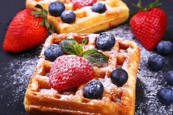 Waffles belgas tradicionais caseiros com frutas frescas, bagas e açúcar em pó na placa preta . — Fotografia de Stock