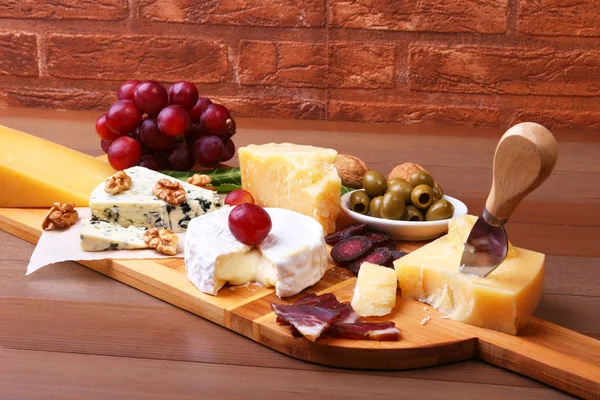 Ассортимент сыра с фруктами, виноградом, орехами и сырным ножом на подносе . — стоковое фото