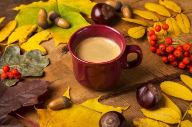 Sonbahar, sonbahar yaprakları, ahşap masa arkasında sıcak bir fincan kahve. Pazar sabahı kahve rahatlatıcı ve hayat dolu..