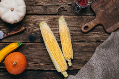 Mısır ve kabak sarı yapraklar ve ahşap arka plan üstten görünüm üzerinde kesme kurulu