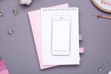Beyaz not defterli cep telefonu, pembe defter ve gri arka plan görünümlü nakış.
