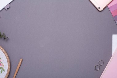 Cep telefonlu gri arkaplan, beyaz not defteri, pembe defter ve nakışlı üst görünüm