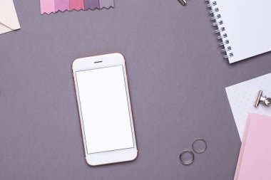 Beyaz not defterli cep telefonu, pembe defter ve gri arka planda nakış.