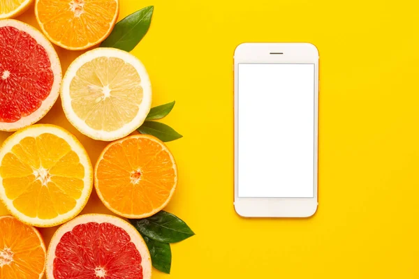 Sarı zemin üzerinde meyve ve cep telefonu, telif alanı, meyve bezi, greyfurt, limon, mandalina ve turuncu üst görüşlü yaz minimumu kompozitonu.