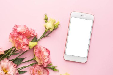 Cep telefonu ve pembe çiçek buketi pastel arka plan görünümünde.