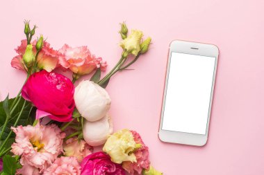 Cep telefonu ve pembe çiçek buketi pastel arka plan görünümünde.
