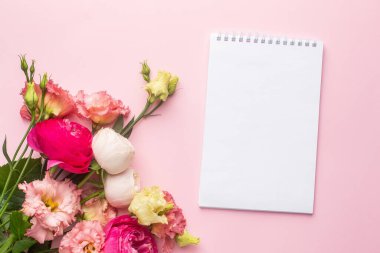 Not defteri ve pembe çiçek buketi pastel arka plan görünümünde