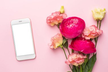 Cep telefonu ve pembe çiçek buketi pastel arka plan görünümünde.