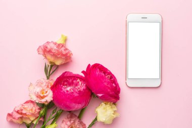 Cep telefonu ve pembe çiçek buketi pastel arka plan görünümünde.