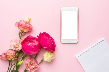 Cep telefonu ve pembe çiçek buketi pastel arka plan görünümünde.