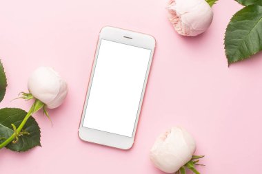 Cep telefonu ve pastel pembe arka planda beyaz güller. Tatil ve aşk öğesi üst görünümü