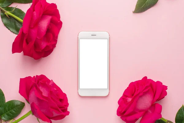 Mobile phone and dark pink rose on a pink background top view