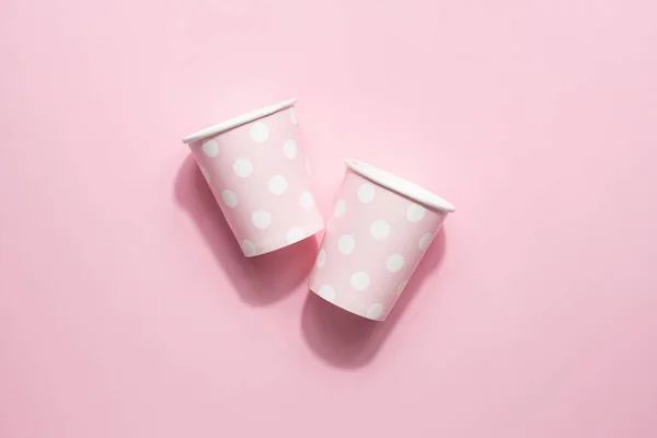 Polka dot disposable paper cups on pink background top view
